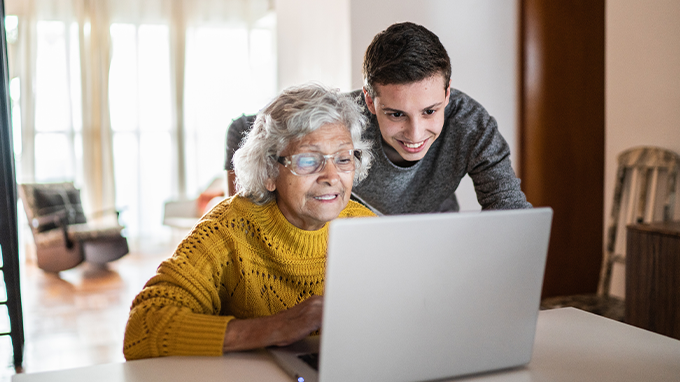 Image of a caregiver assisting a client with a laptop to depict the importance Technology Tools to Help Companion Caregivers Support their Clients